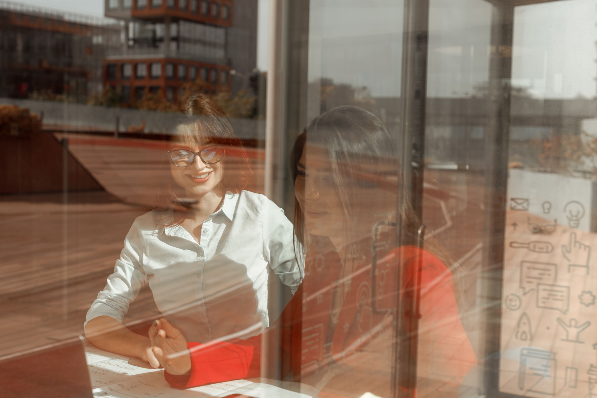 Two young women, an engineer and an architect, are working together on a construction project in a bright and modern architecture and engineering company office